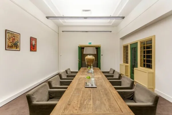 Vergaderruimte met een lange houten tafel, moderne stoelen en groene deuren in een pand aan de Ceresstraat 13.