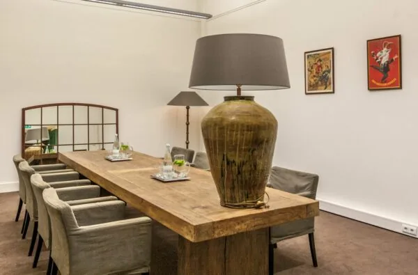 Vergaderruimte aan de Ceresstraat 13 met een robuuste houten tafel, zes stoelen, grote tafellamp en decoratieve kunst aan de muur.