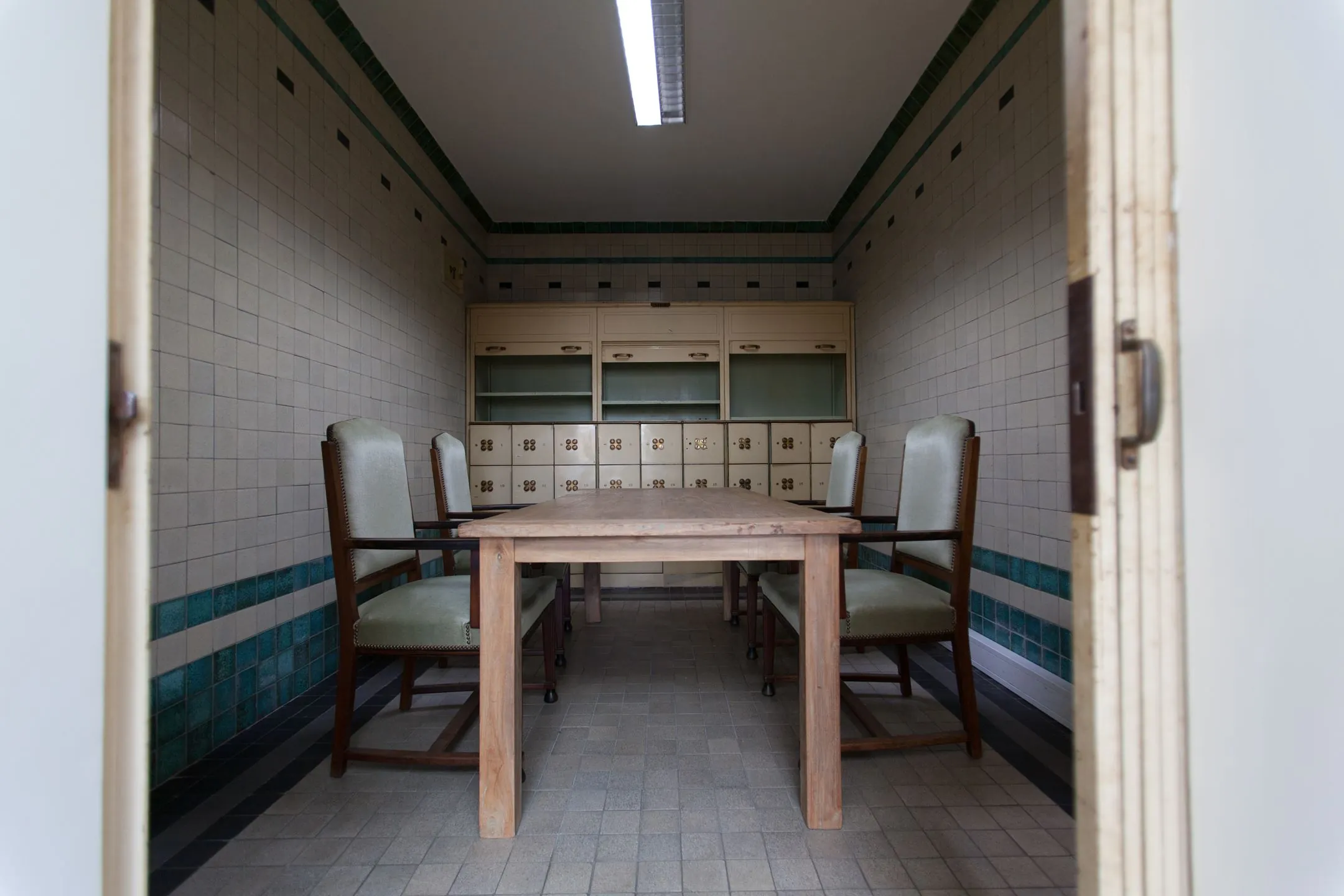 Vergaderruimte met vier stoelen, een houten tafel en betegelde muren in Ceresstraat 13.