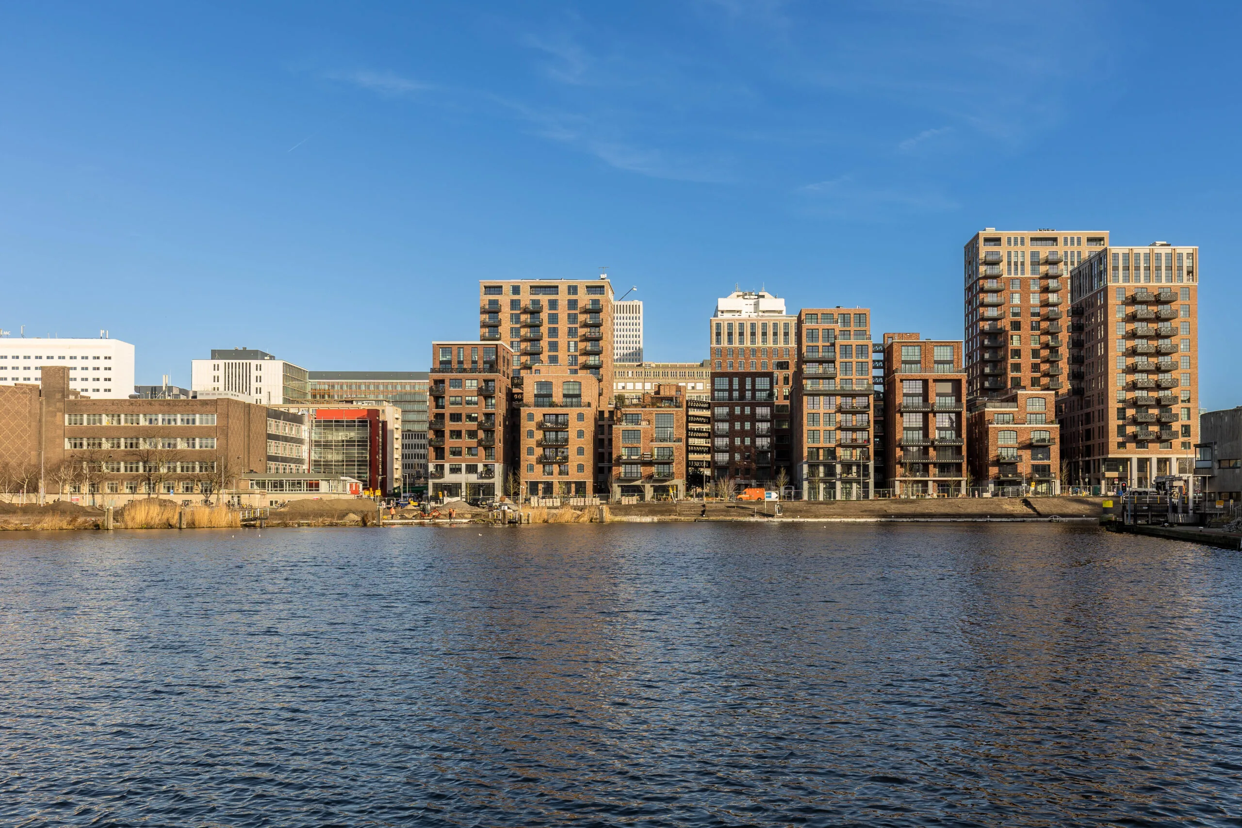 Moderne appartementengebouwen aan het water bij Coolhaven in Rotterdam onder een heldere blauwe lucht.