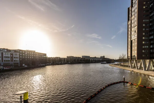 Zonsondergang boven de Coolhaven in Rotterdam met hoge en lage gebouwen langs het water.