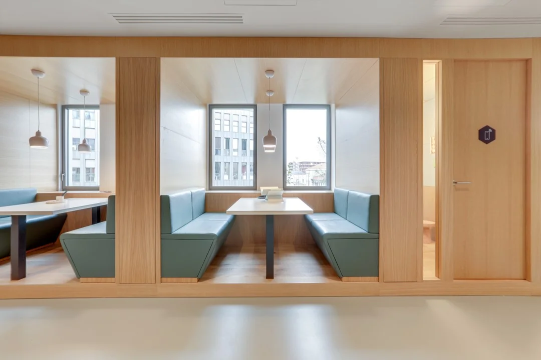 Modern ingerichte zitnisjes met turquoise banken en houten wanden in een kantoorruimte aan de Coolsingel 65.