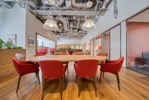 Moderne vergaderruimte in Coolsingel 65 met houten tafel, rode stoelen en industriële plafondafwerking.