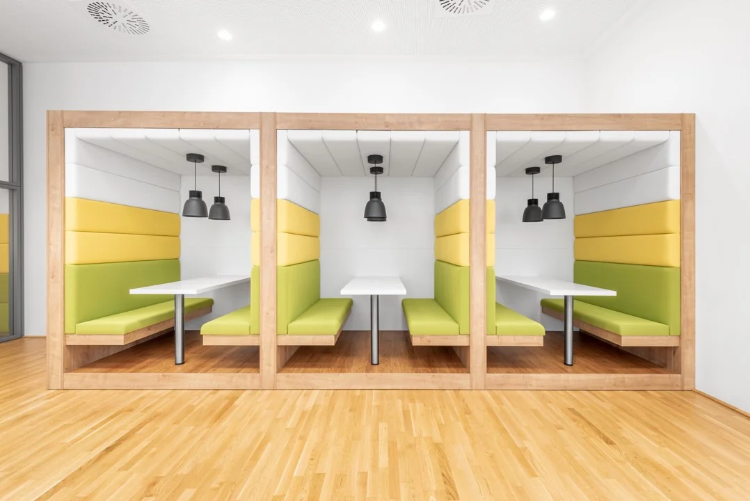 Drie moderne, houten werk- of overlegpods met felgroene en gele bekleding in een open kantoorruimte aan de Coolsingel 65.