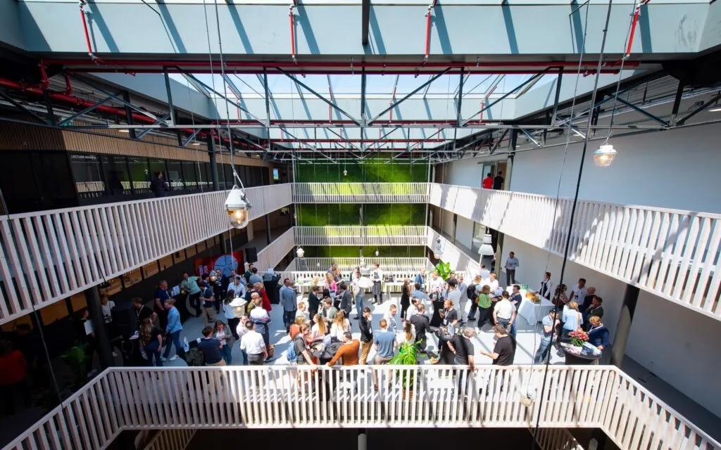 Overzichtsfoto van een drukbezocht netwerkevenement tijdens het HortiHeroes Hero Festival in een lichte, moderne binnenruimte met groenaccenten.
