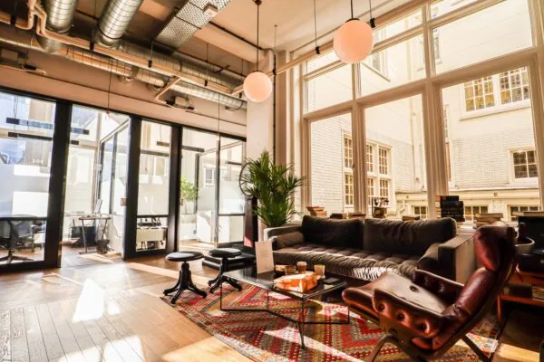 Moderne loungehoek met designmeubilair en grote ramen in kantoorruimte DAM 1.