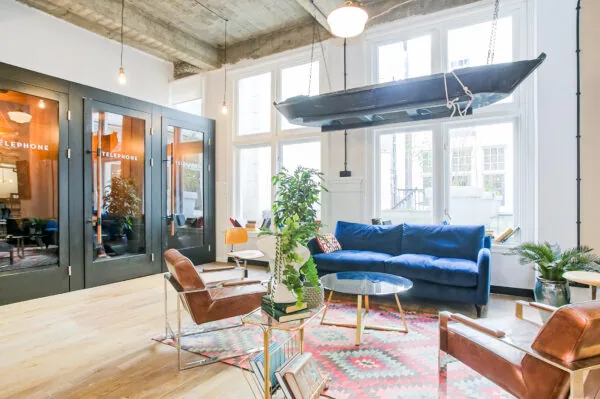 Stijlvol ingerichte lounge met blauw bankstel, hangende boot en glazen belcabines in werkruimte DAM 3.
