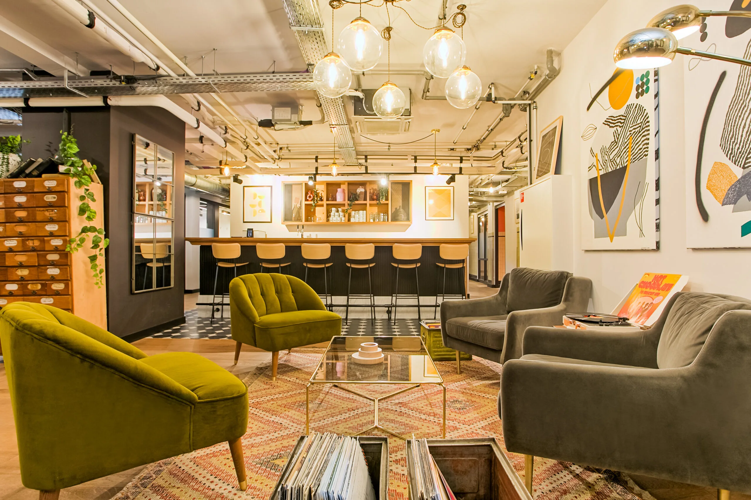 Stijlvol ingerichte lounge van DAM 4 met retro meubilair, kunst aan de muur en een bar op de achtergrond.