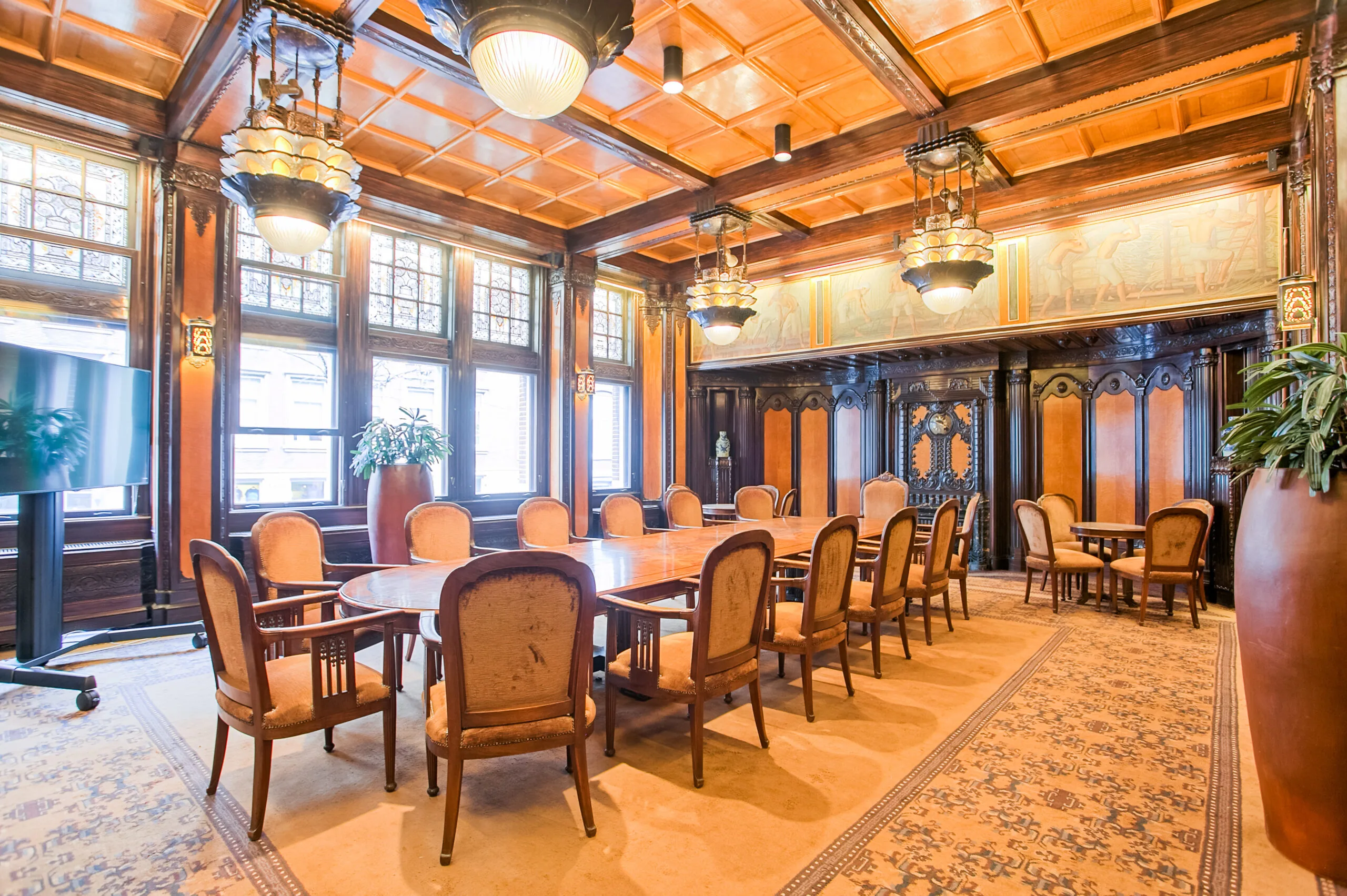 Vergaderruimte DAM 5 met klassieke houten lambrisering, een lange tafel en sierlijke plafondlampen.