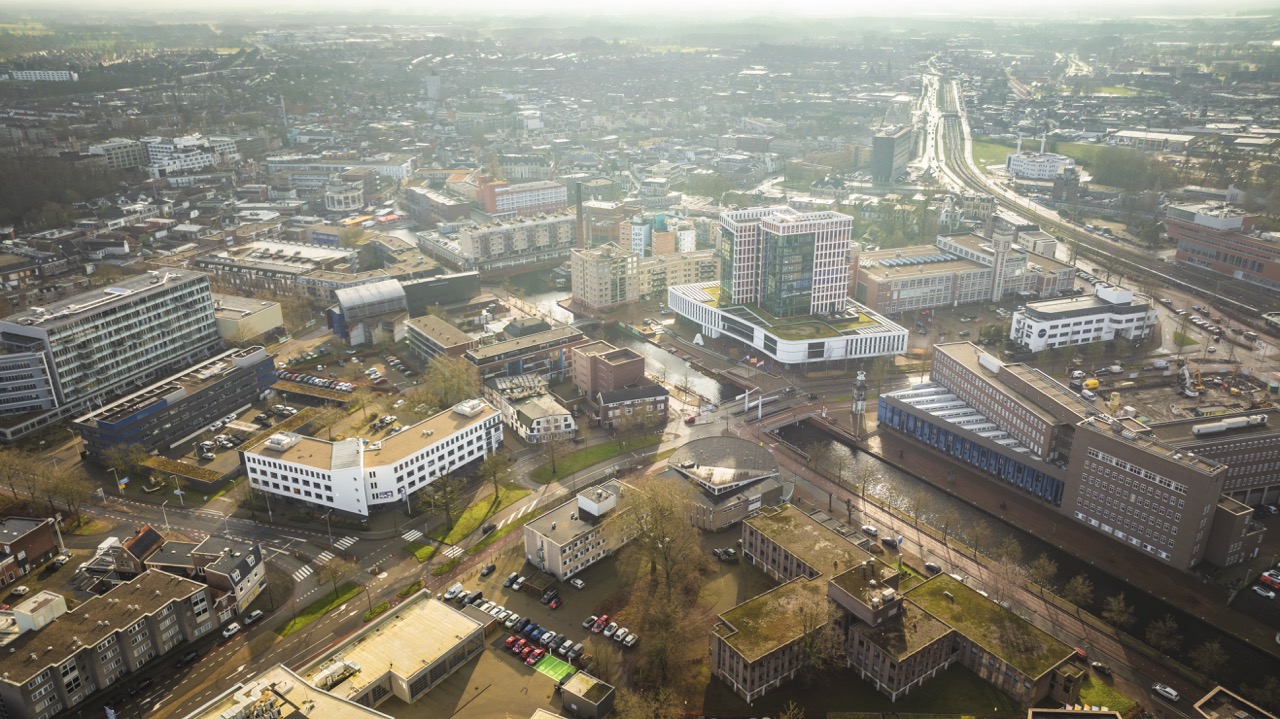 Luchtfoto van het centrum van Enschede met moderne en historische gebouwen rondom het stationsgebied.