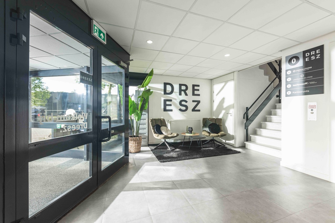 Moderne en lichte entreehal van het kantoorpand Dreesz met zitgelegenheid en bedrijfsnaam op de muur.