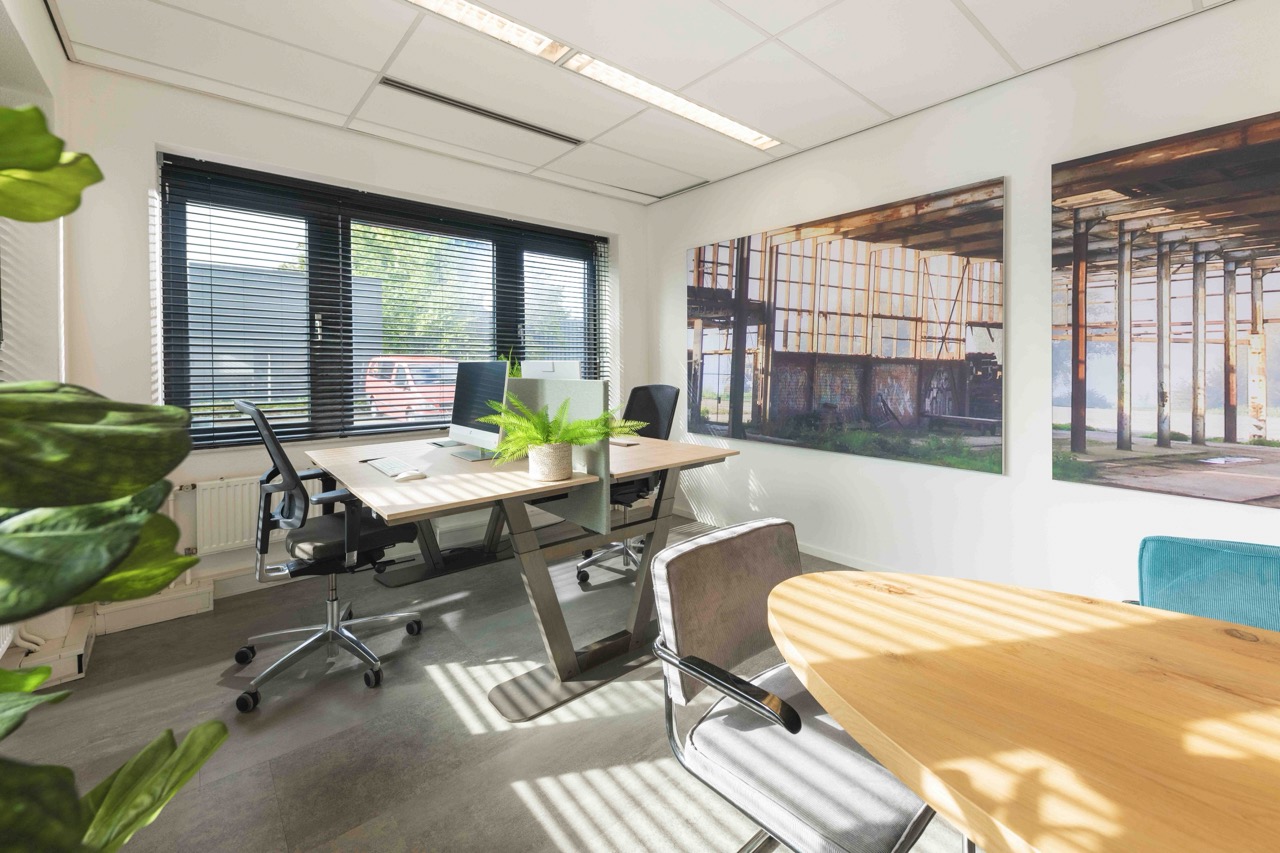 Modern en licht kantoor met houten bureaus, bureaustoelen, grote raamdecoratie en industriële wandfoto's.