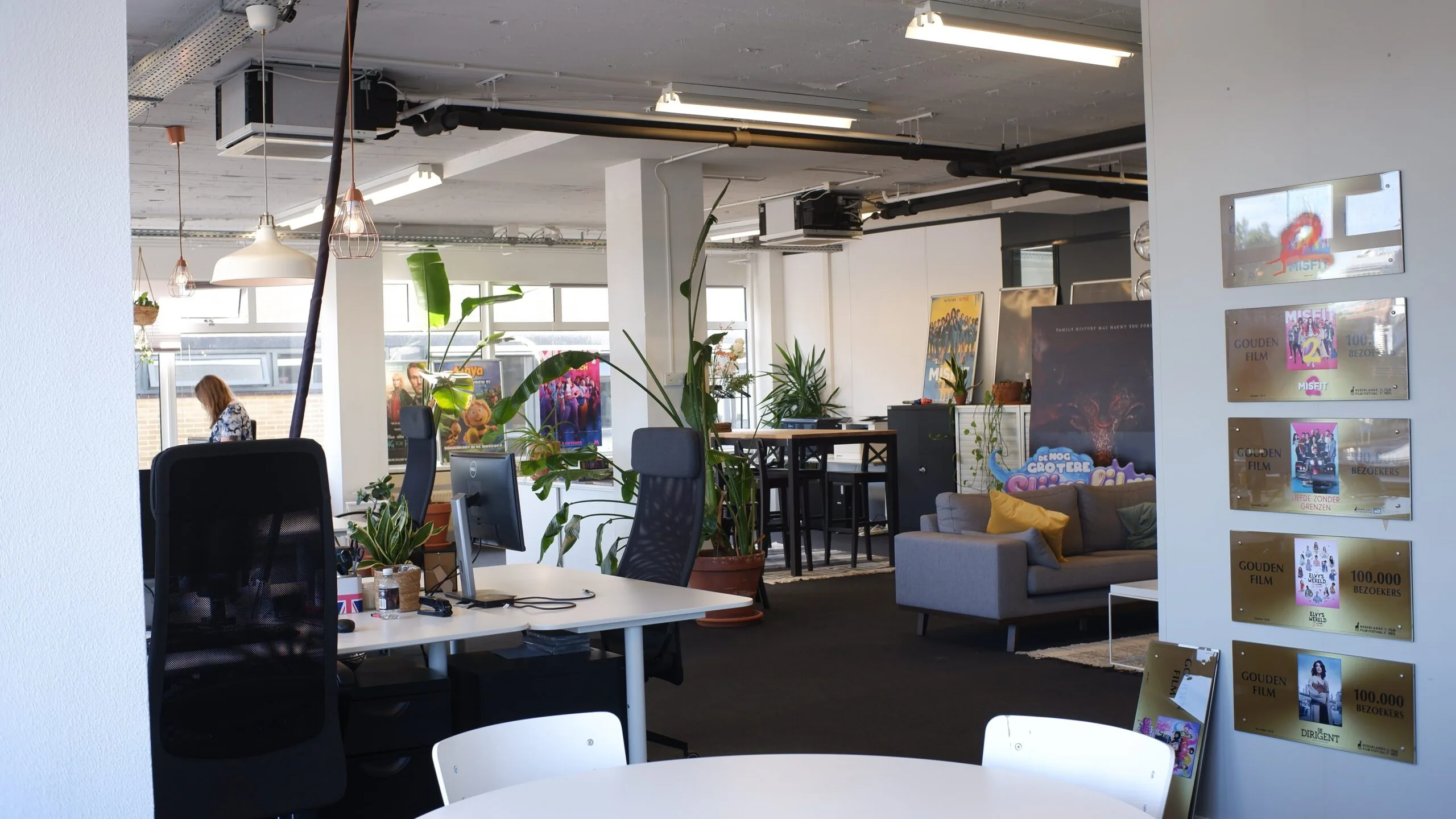 Moderne en kleurrijke kantoorruimte met planten, filmposters en Gouden Film-awards aan de muur.