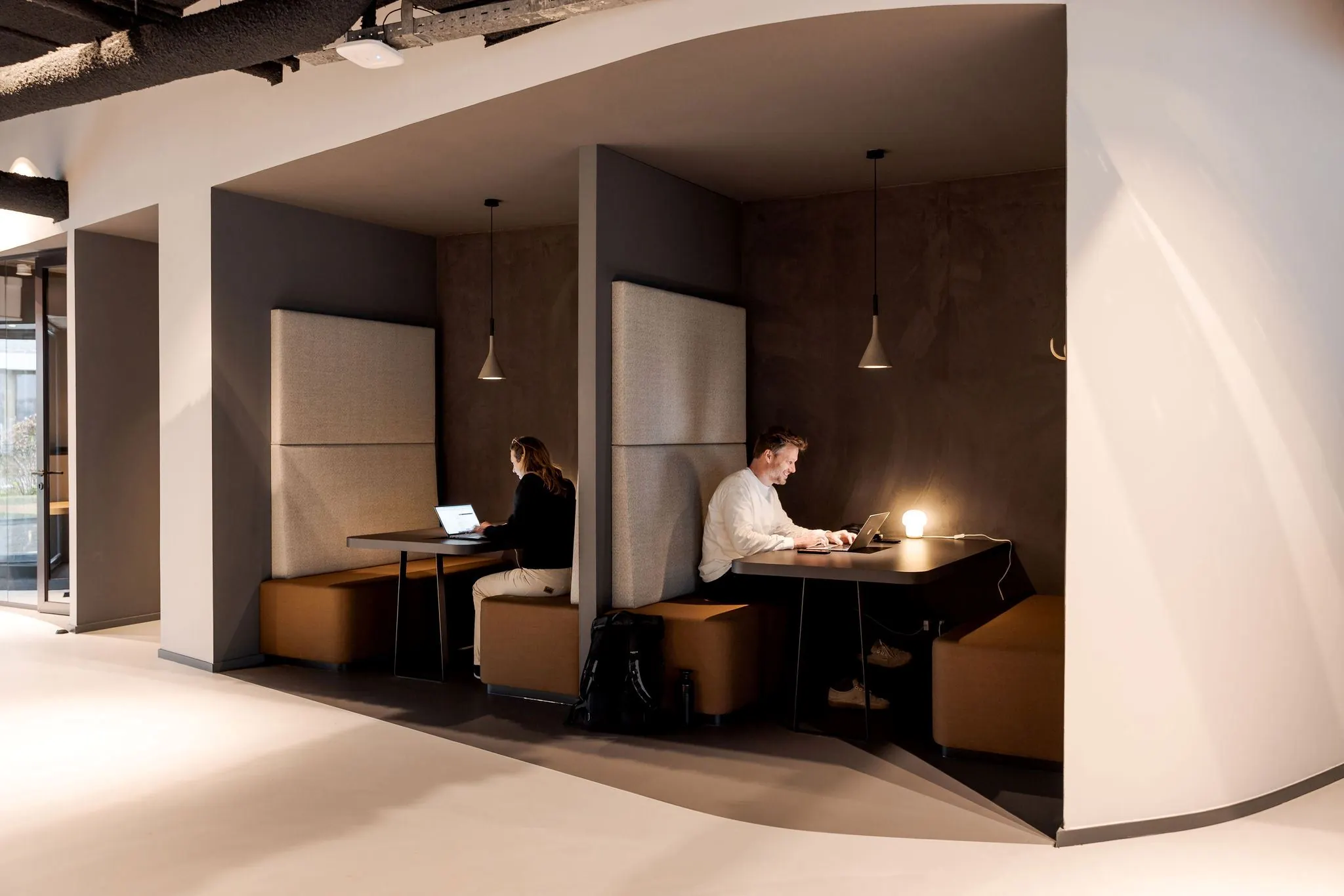 Twee mensen werken op laptops in moderne werkpleknissen aan de Daalsesingel 51.