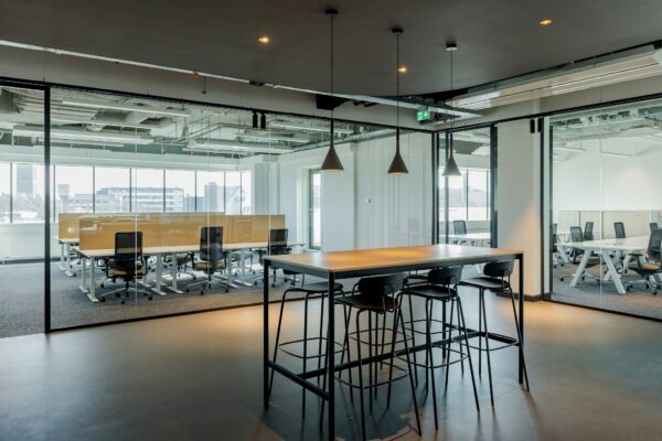 Moderne kantoorruimte aan de Daalsesingel 51 met glazen wanden, werkplekken en een hoge tafel met barkrukken.