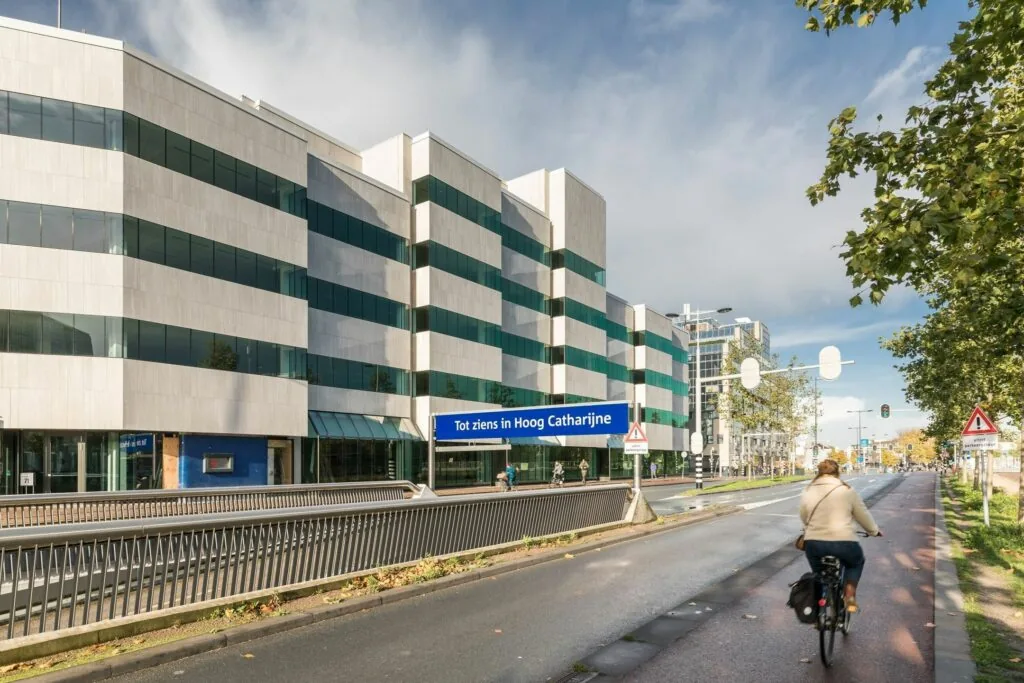 Fietser op het fietspad langs de Daalsesingel in Utrecht met het kantoorgebouw op nummer 51 en een bord “Tot ziens in Hoog Catharijne”.