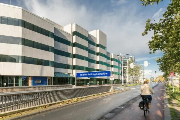 Fietser op het fietspad langs de Daalsesingel in Utrecht met het kantoorgebouw op nummer 51 en een bord “Tot ziens in Hoog Catharijne”.