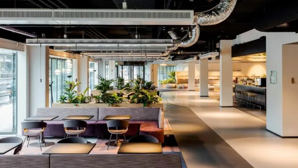 Moderne en open kantoorruimte aan de Daalsesingel 51 met zithoeken, veel planten en een koffiebar.