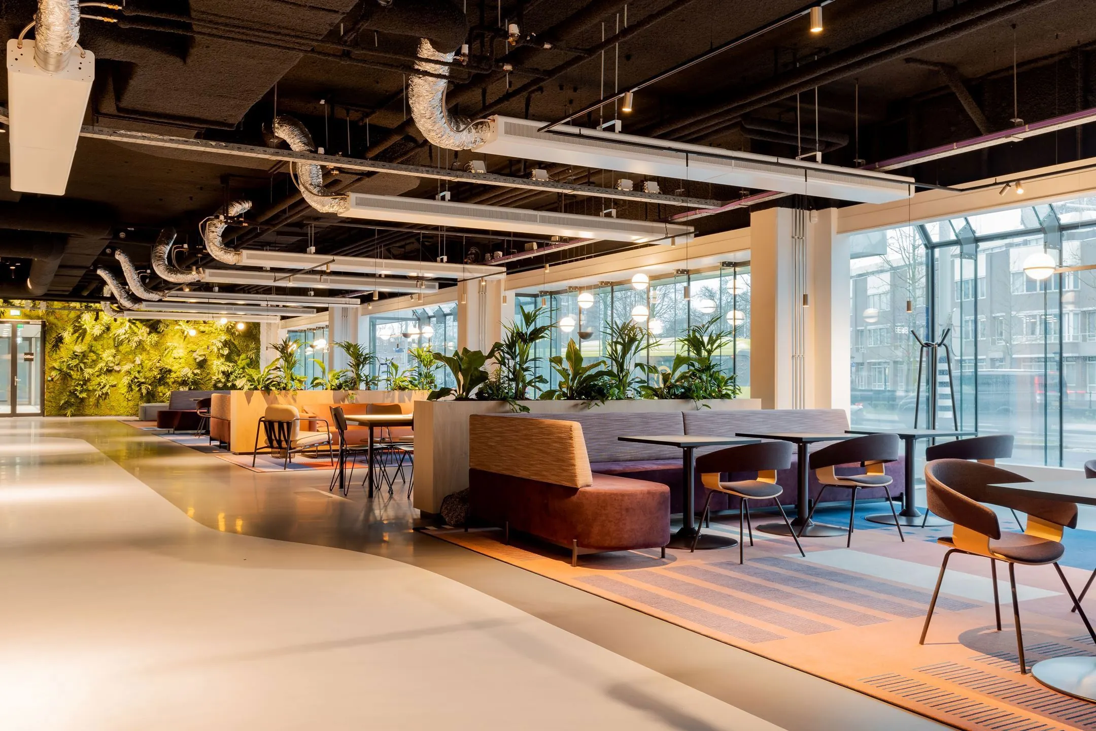 Moderne en open kantoorruimte aan de Daalsesingel 51 met zitgedeeltes, veel planten en grote ramen met daglicht.