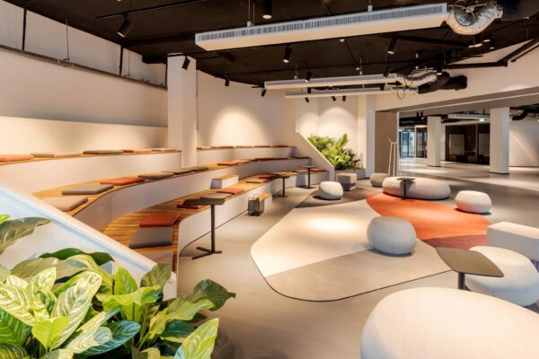 Moderne en open kantoorlounge aan de Daalsesingel 51 met tribunezitplaatsen, zachte poefjes en veel natuurlijke elementen.
