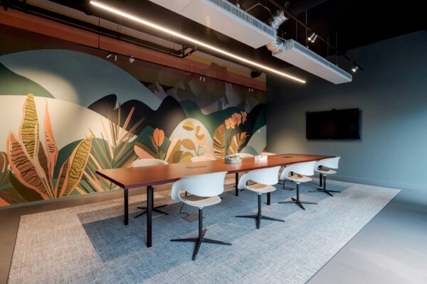 Vergaderruimte aan de Daalsesingel 51 met lange tafel, moderne stoelen en kleurrijk plantenmotief op de muur.