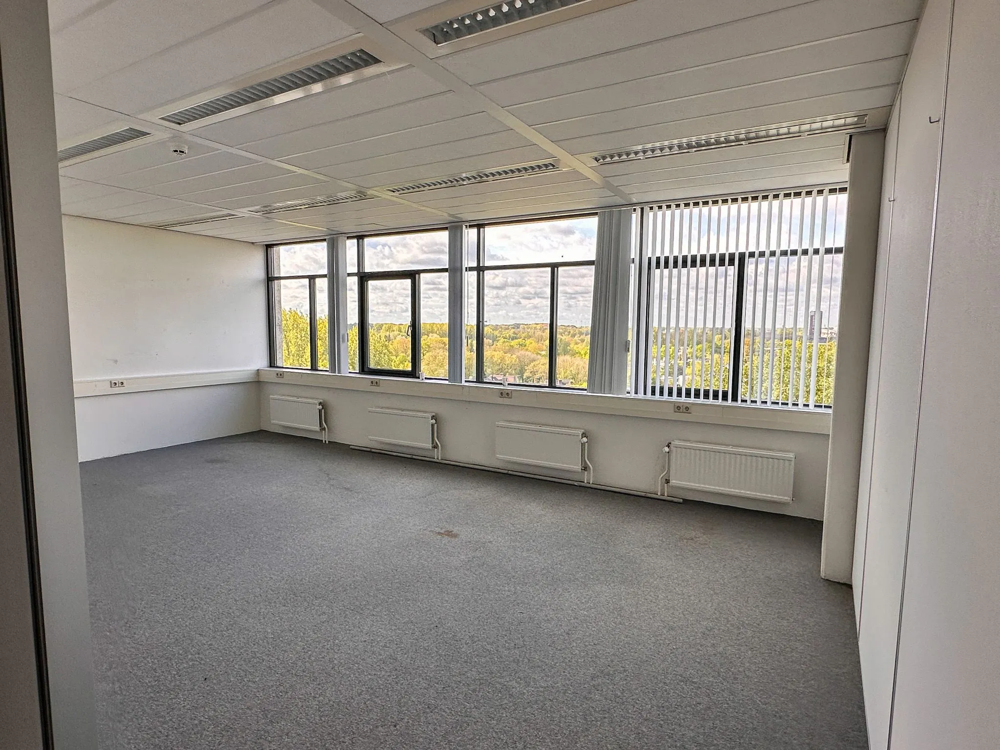 Leeg kantoor met grote ramen en uitzicht op groen landschap aan de Daltonlaan 200.
