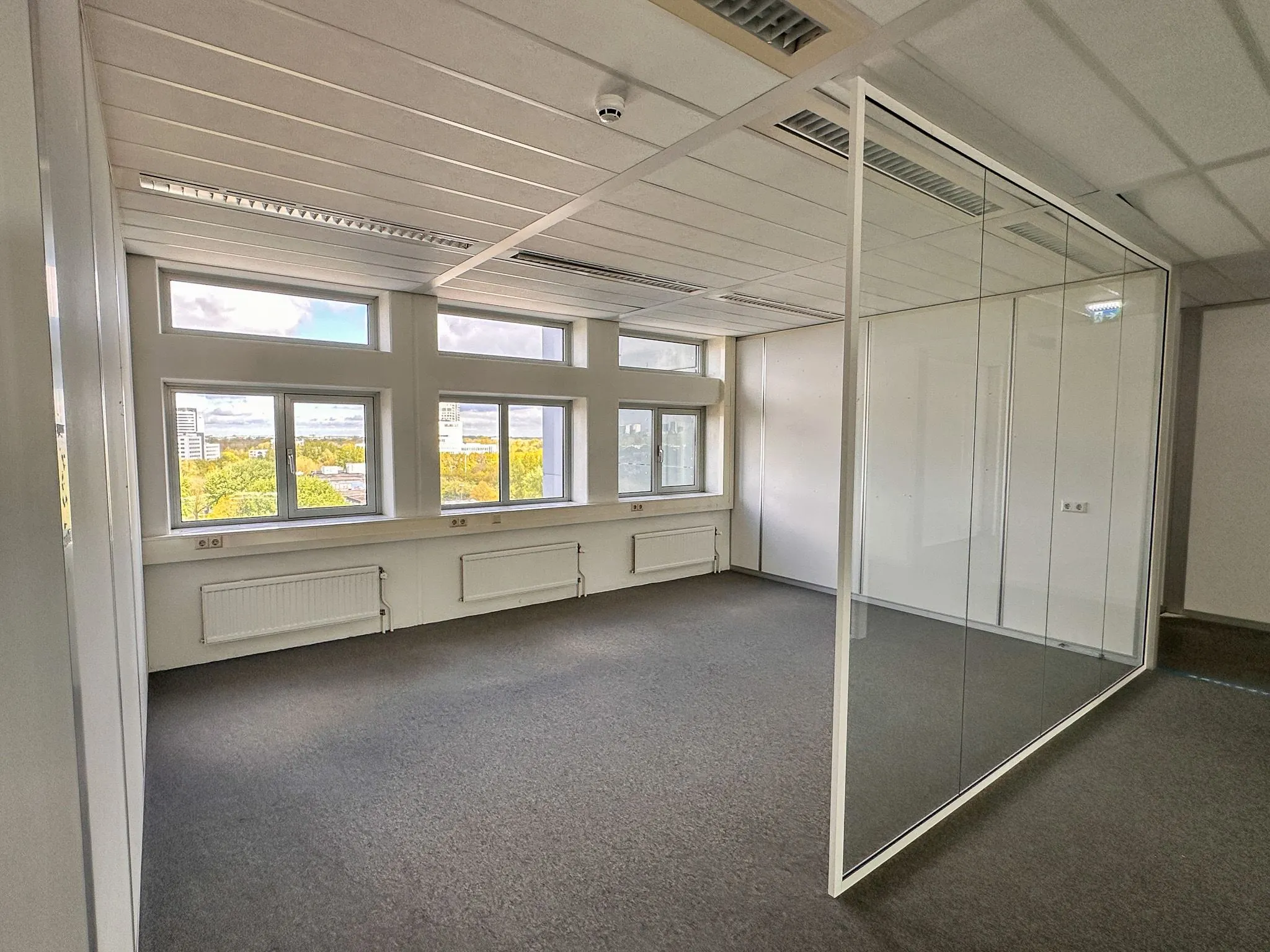 Lichte kantoorruimte aan de Daltonlaan 200 met grote ramen en een glazen scheidingswand.