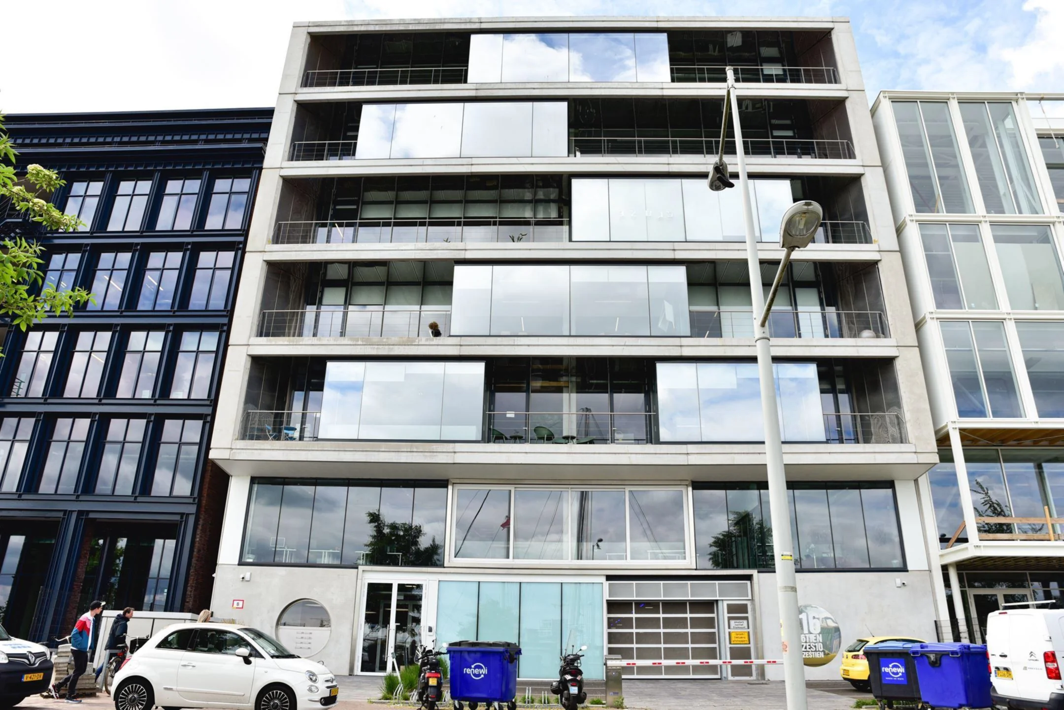 Vooraanzicht van het moderne kantoorgebouw aan de Danzigkade 16 met glazen gevel en geparkeerde voertuigen op straat.