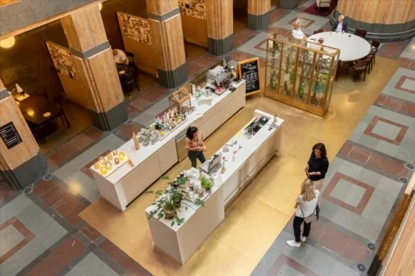 Centrale hal van De Rode Olifant met een moderne koffiebalie, zittende gasten en art-deco interieur.