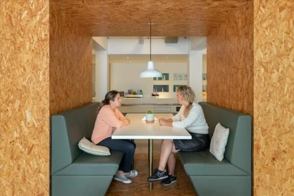 Twee vrouwen zitten tegenover elkaar in een nis met houten wanden in De Rode Olifant.