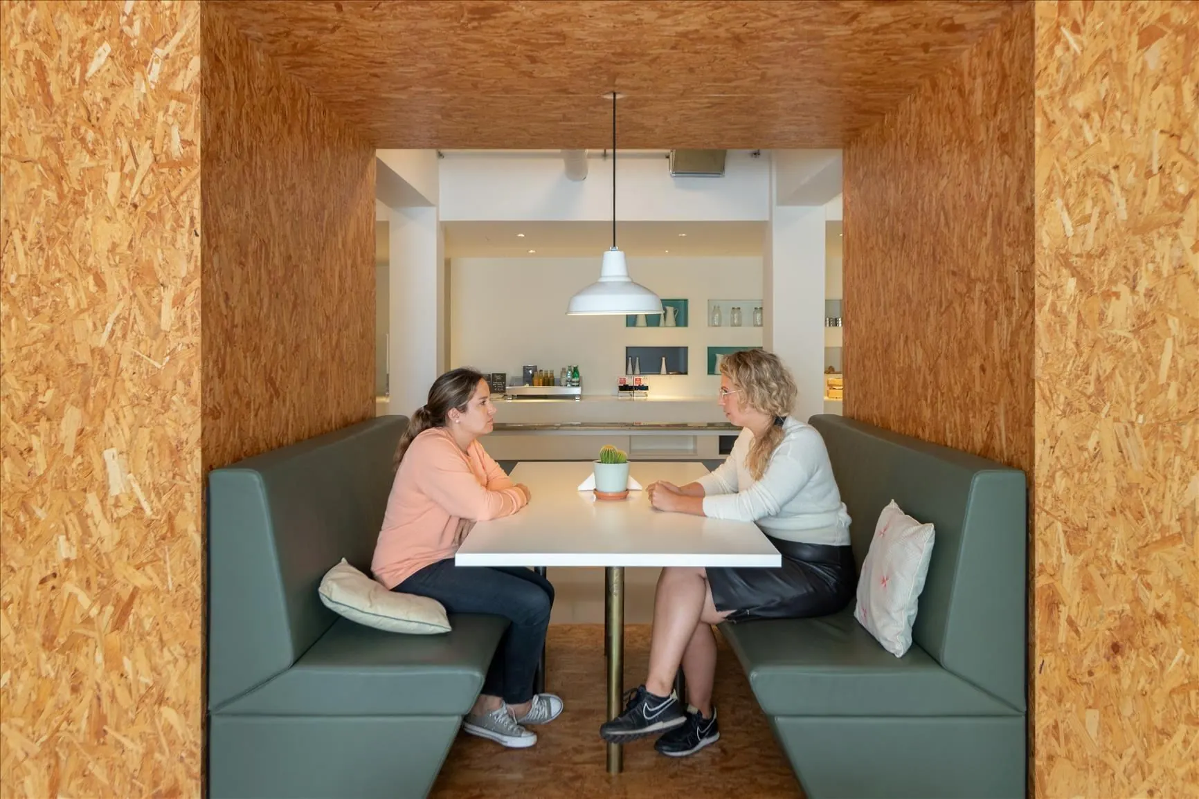 Twee vrouwen zitten tegenover elkaar in een nis met houten wanden in De Rode Olifant.