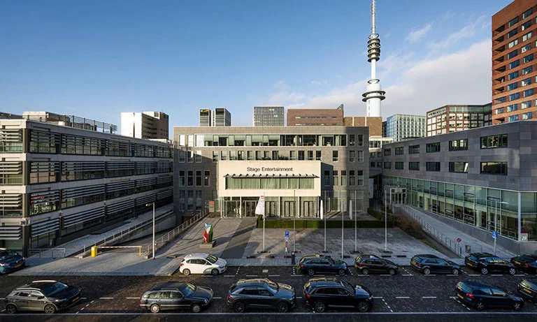 Voorgevel van het Stage Entertainment-gebouw aan de De Boelelaan 30 in Amsterdam, met geparkeerde auto's op de voorgrond.