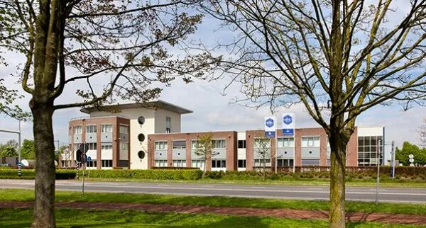 Modern kantoorpand aan de Dr. Nolenslaan 157, gefotografeerd vanaf de overkant van de weg tussen bomen door.