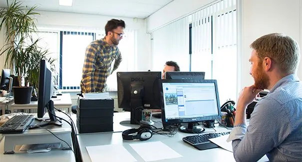 Kantoorruimte aan de Dr. Nolenslaan 157 met drie mannen werkend achter computers.