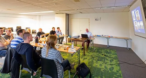 Een groep mensen volgt een presentatie in een vergaderruimte aan de Dr. Nolenslaan 157.