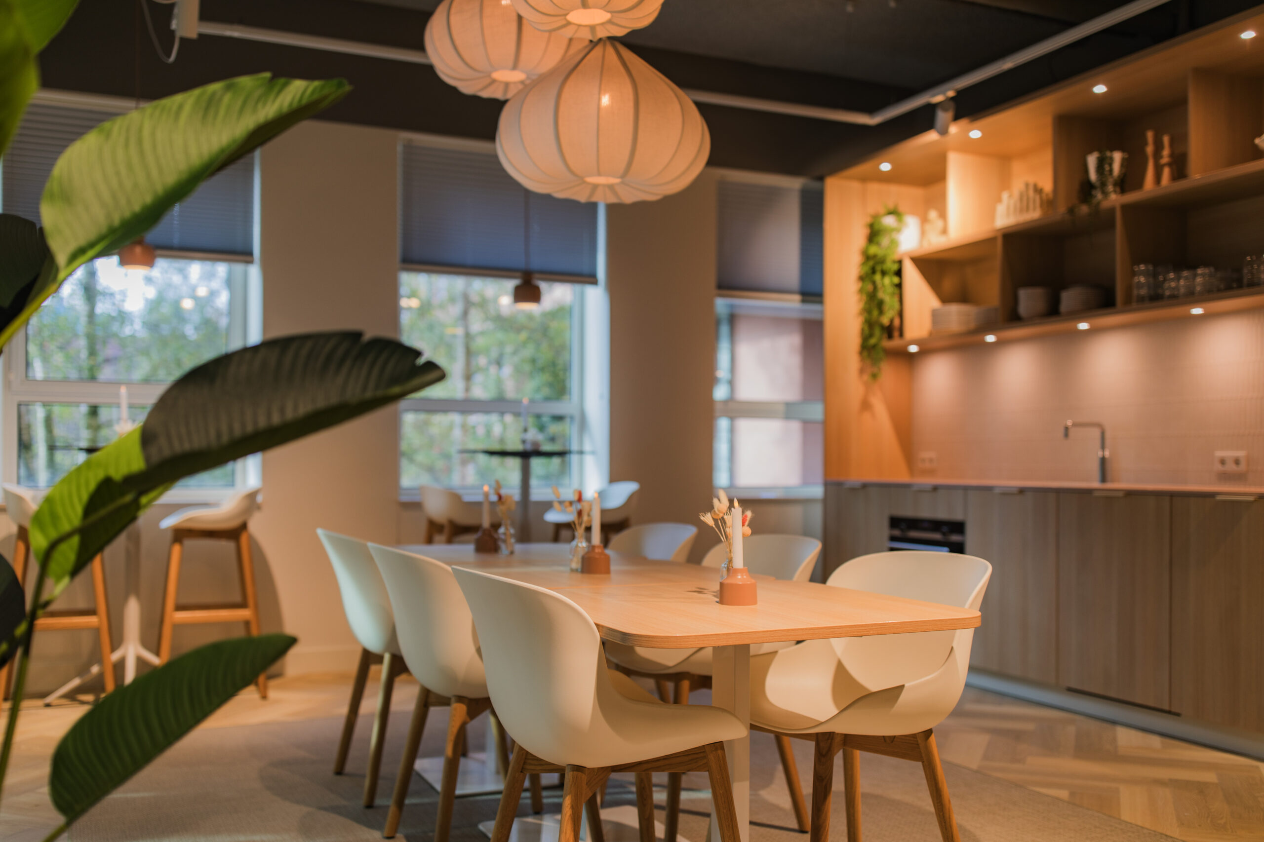 Modern shared kitchen and dining area at Hullenberg 103 with wooden furniture, pendant lights, and soft natural lighting.