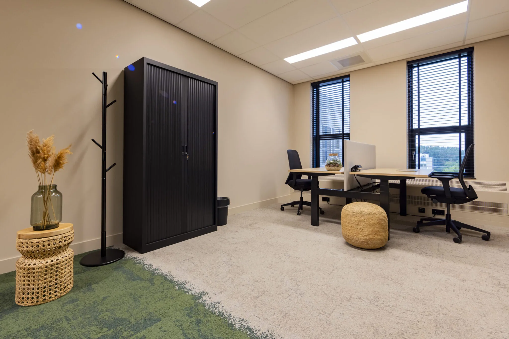 Modern tweepersoons kantoor in EO Diemen met neutrale tinten, zwarte meubels en decoratieve accenten.