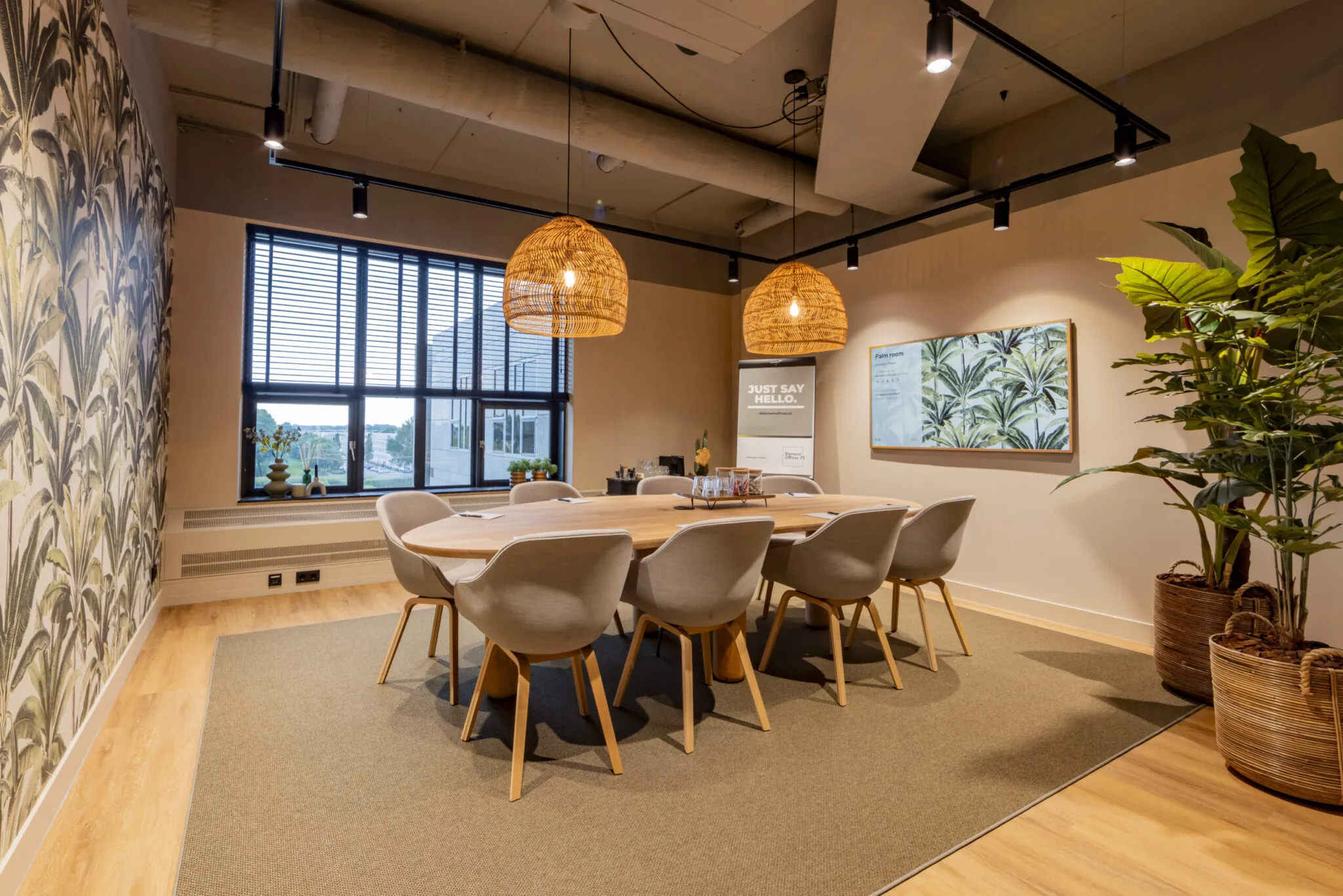 Moderne vergaderruimte in EO-kantoor Diemen met grote houten tafel, designstoelen en tropische decoratie.