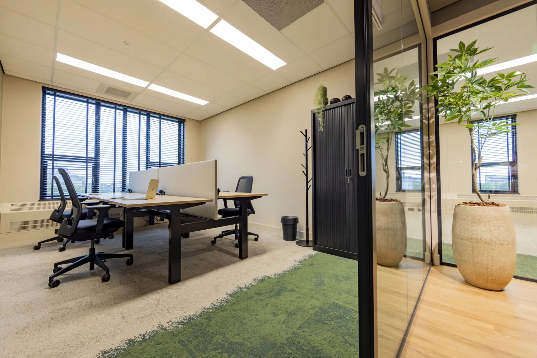 Moderne kantoorruimte in EO Diemen met werkplekken, bureaustoelen, planten en grote ramen met jaloezieën.