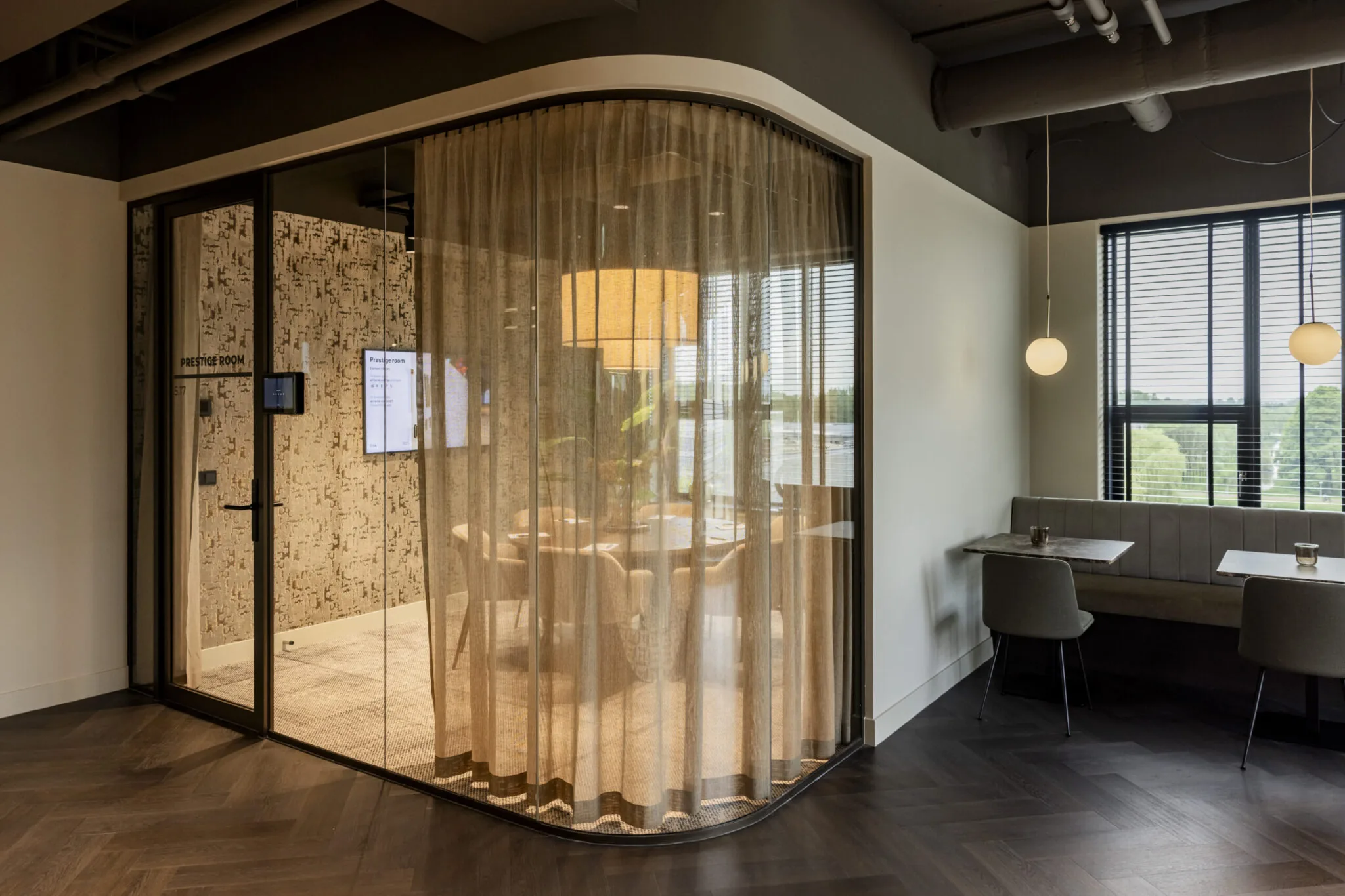 Modern ingerichte vergaderruimte genaamd "Prestige Room" met glazen wanden en een sfeervolle zithoek ernaast in kantoorgebouw EO Diemen.
