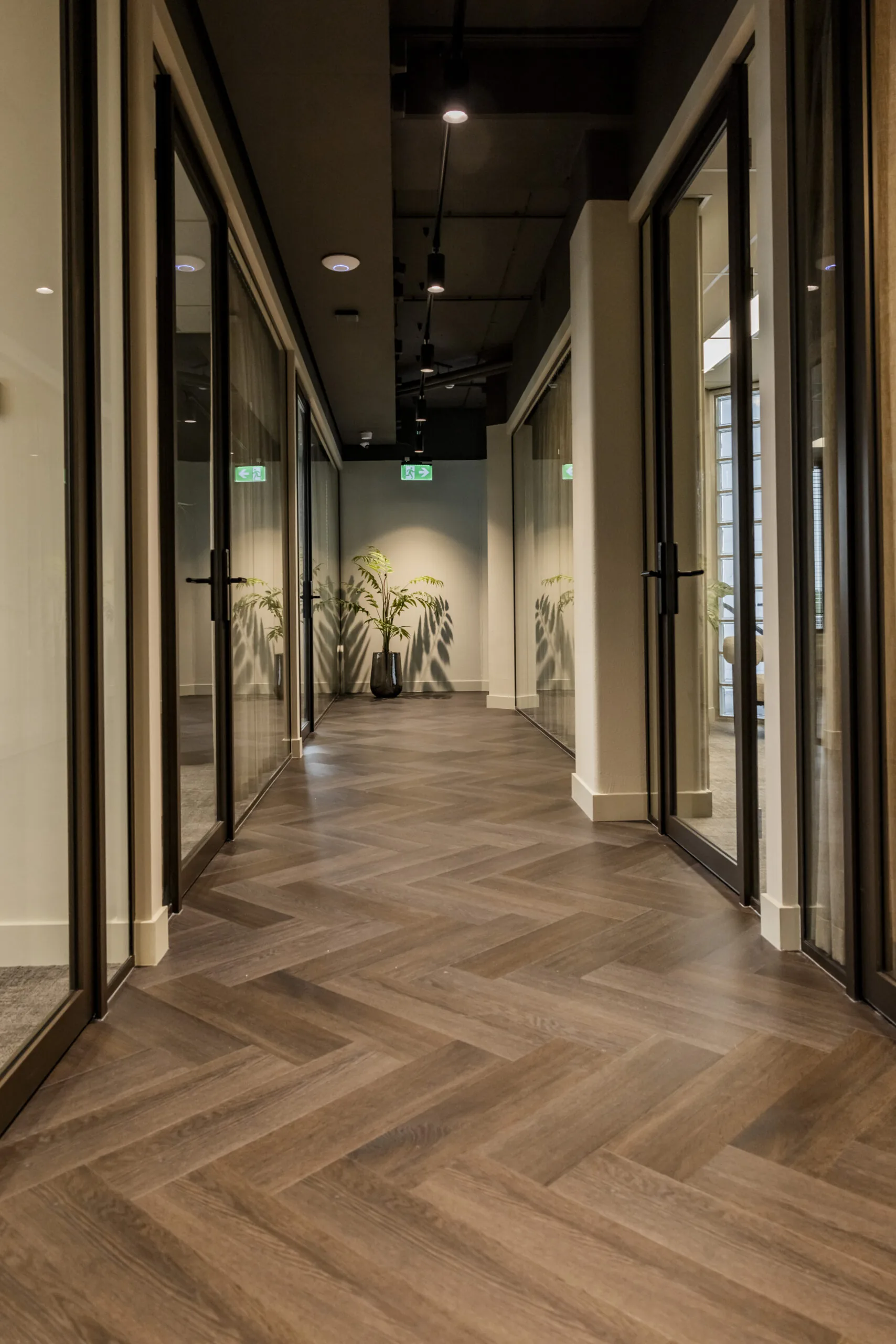 Moderne kantoorhal in EO Diemen met visgraatvloer, glazen deuren en planten.