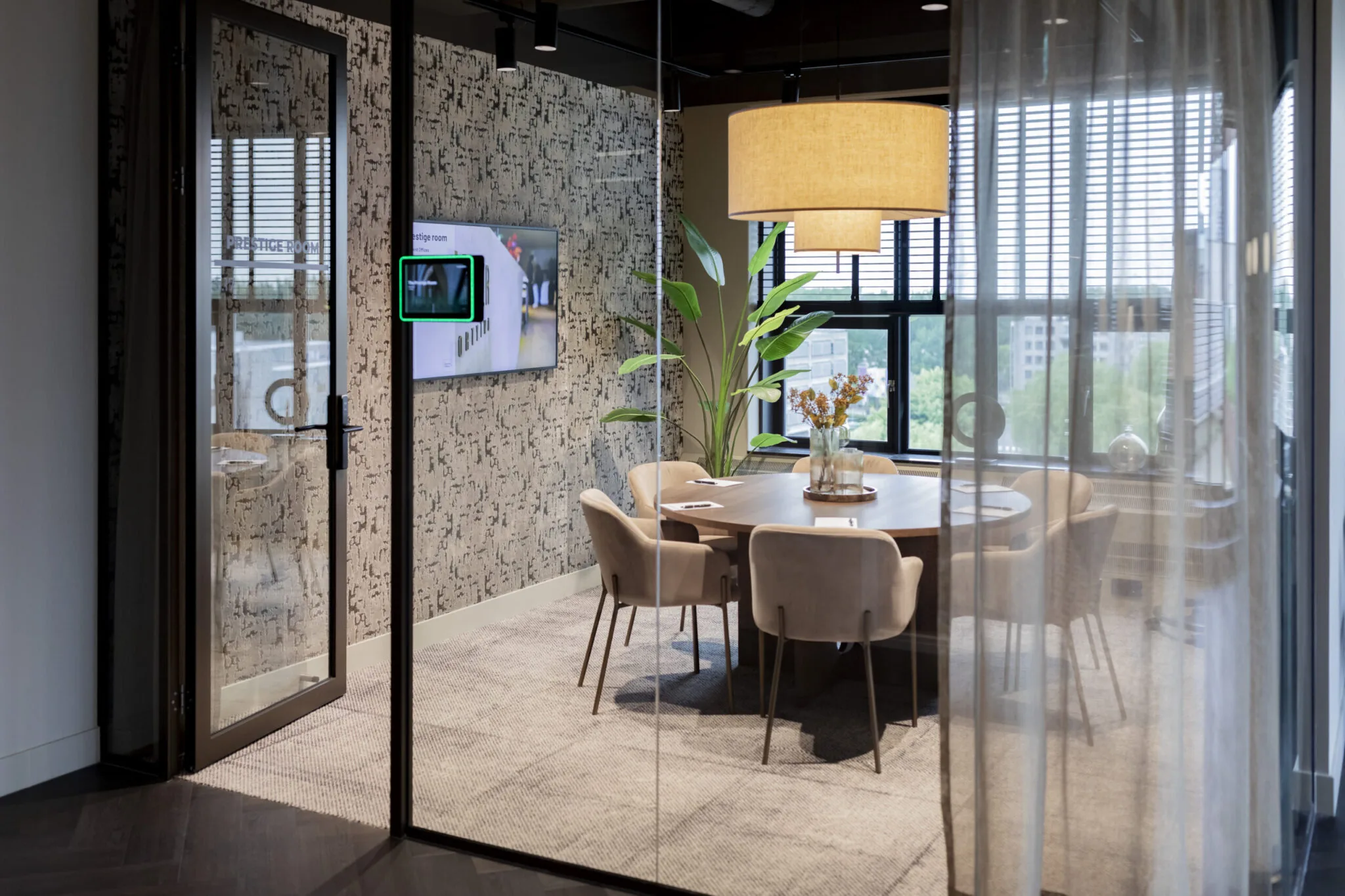 Vergaderruimte genaamd "Prestige Room" in EO Diemen met ronde tafel, zes stoelen, hanglamp en decoratieve planten.