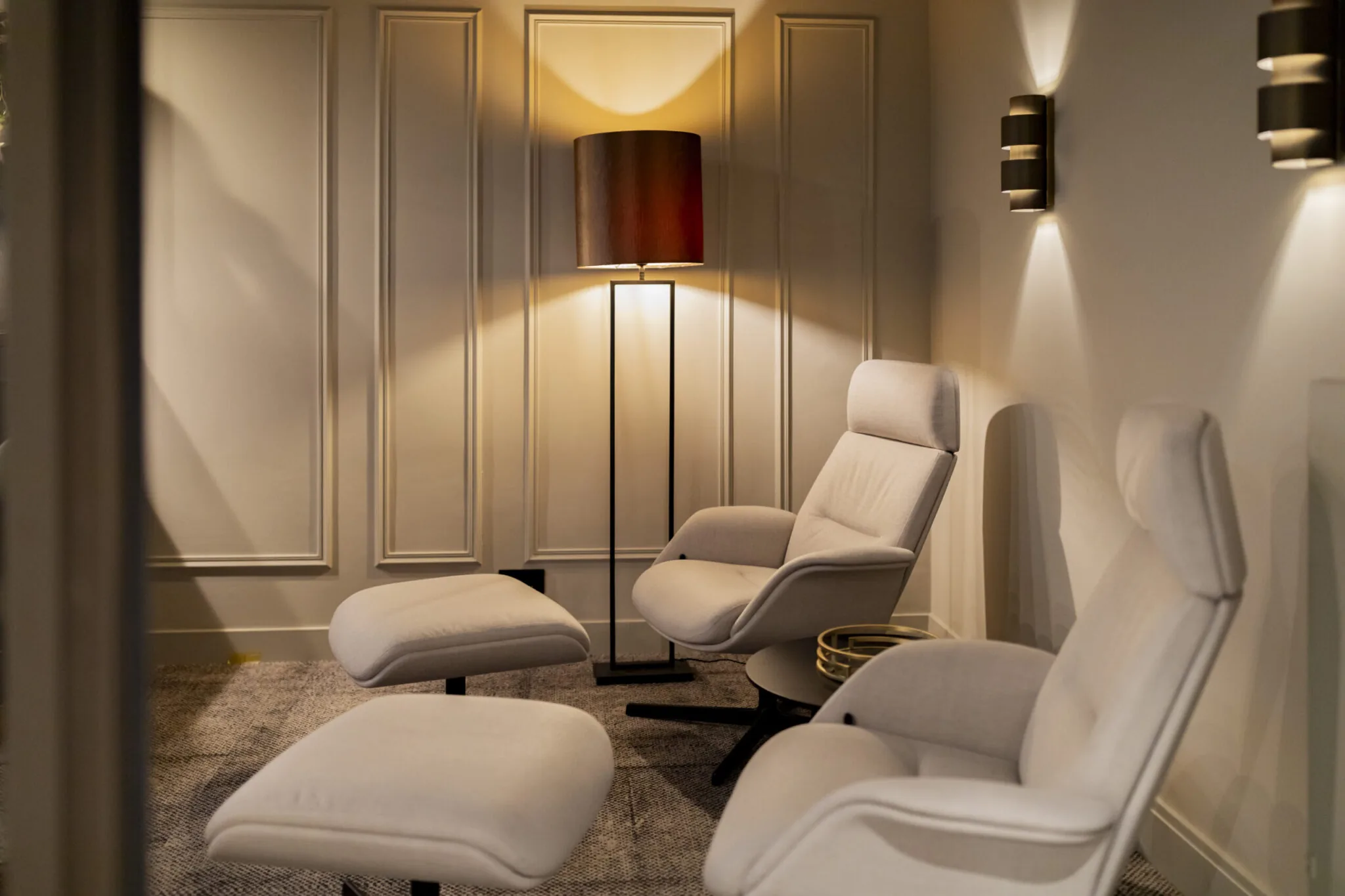 Luxe loungehoek in EO Diemen met beige relaxfauteuils, voetenbankjes en warme sfeerverlichting.
