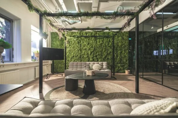 Moderne loungehoek aan de Egbert Gorterstraat met groene moswand, glazen wanden en sfeervolle zithoek.