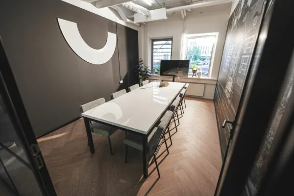 Vergaderruimte aan de Egbert Gorterstraat met lange witte tafel, moderne stoelen en groot wandkunstwerk.