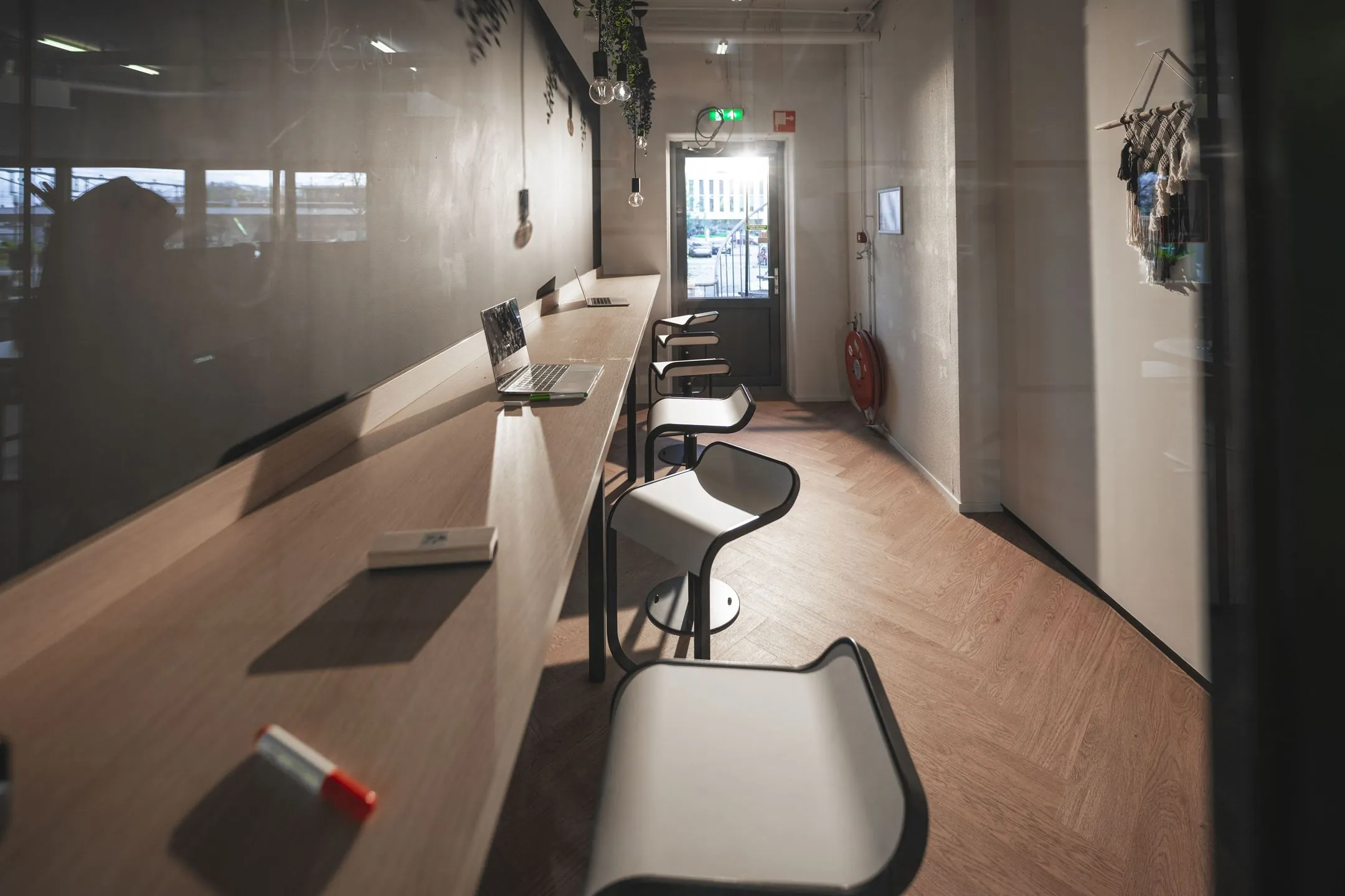 Moderne werkruimte aan de Egbert Gorterstraat 2-14 met hoge werktafel, barkrukken, laptop en groot schoolbord.