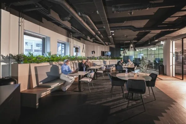 Moderne gezamenlijke werkruimte aan de Egbert Gorterstraat 2-14 met zitplekken, plantenbakken en werkende mensen.