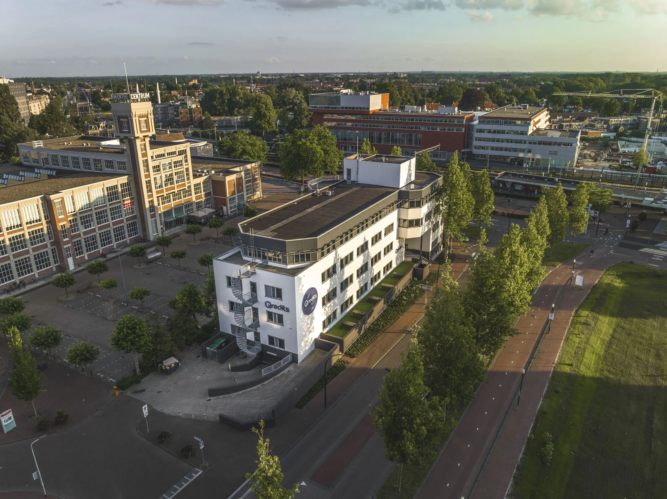 Luchtfoto van het gebouw aan de Egbert Gorterstraat 2-14 in Enschede, met het voormalig postkantoor en het stationsgebied op de achtergrond.