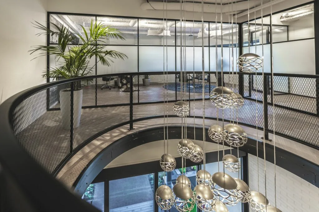 Moderne kantoorruimte aan de Egbert Gorterstraat met glazen wanden, industriële balustrade en hangende designlampen.