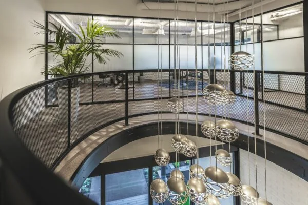 Moderne kantoorruimte aan de Egbert Gorterstraat met glazen wanden, industriële balustrade en hangende designlampen.